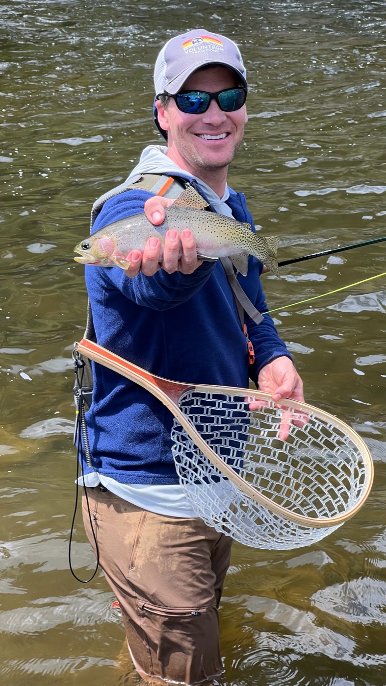 A participant holding up a fish caught fly fishing